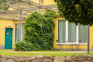 a yellow building with a bench in front of a bush at Doppelzimmer 12 Gästehaus Mühlenstein in Bad Sülze