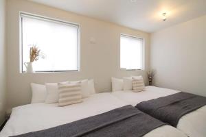 - une chambre avec un grand lit blanc et 2 fenêtres dans l'établissement bHOTEL Komachi - New Apt for 6ppl near PeacePark, à Hiroshima