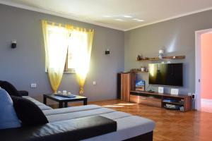 een woonkamer met een bank en een flatscreen-tv bij Holiday House Risika Seaview in Risika