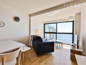 uma sala de estar com um sofá, uma mesa e uma televisão em Appartement au pied de la plage, vue imprenable sur la mer em Les Sables-dʼOlonne