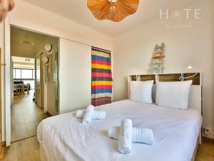 una camera da letto con un grande letto bianco con asciugamani di Appartement au pied de la plage, vue imprenable sur la mer a Les Sables-dʼOlonne