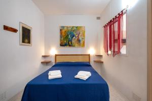 a bedroom with a blue bed with two towels on it at Villa Ada Depandance 1 in Punta Prosciutto