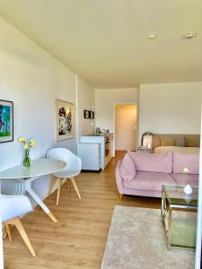 ein Wohnzimmer mit einem rosa Sofa und einem Tisch in der Unterkunft Appartement mit traumhaftem Kieler Förde Blick in Kiel