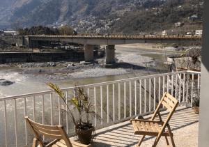 2 sillas sentadas en un balcón con vistas al río en Outdoor Adventures Resort en Muzaffarabad