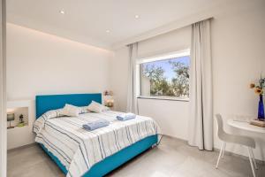um quarto branco com uma cama azul e uma janela em Relais Mamma Mia em Massa Lubrense