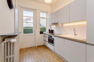 cocina con armarios blancos, ventana y fregadero en Villa Manalou Glv, en Wenduine 12 fotos más