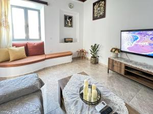 a living room with a couch and a tv at La Casa di villagio in Koskinou