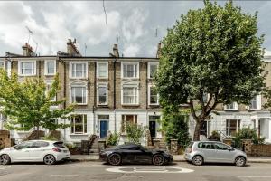 3 voitures garées devant un grand bâtiment dans l'établissement Spacious 3 Bedroom Regents Park Apartment, à Londres