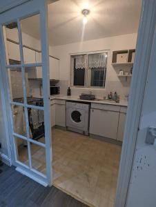 a kitchen with a washer and dryer in a room at Modern ground floor flat in Cranford