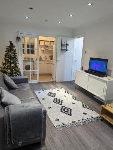 a living room with a couch and a christmas tree at Modern ground floor flat in Cranford
