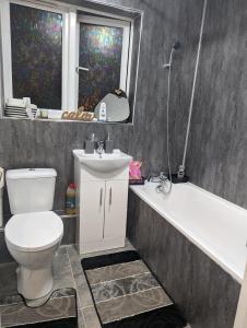 a bathroom with a toilet and a tub and a sink at Modern ground floor flat in Cranford