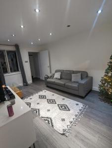 a living room with a couch and a christmas tree at Modern ground floor flat in Cranford