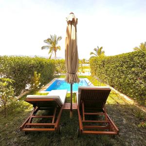 Ma‘mūrahにあるHawana Salalah luxury 1BR TH with private poolのスイミングプールの隣に椅子2脚とパラソル1本