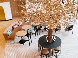 a tree in a room with tables and chairs at Novotel Paris Suresnes Longchamp in Suresnes