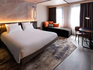 een hotelkamer met een groot bed en een bank bij Novotel Paris Suresnes Longchamp in Suresnes