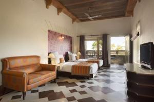 a bedroom with a bed and a chair and a television at Ramada Udaipur Resort & Spa in Udaipur