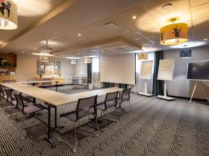 une salle de conférence avec une grande table et des chaises dans l'établissement Novotel Paris Suresnes Longchamp, à Suresnes