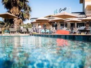 una piscina con mesas, sillas y sombrillas en ibis La Ciotat, en La Ciotat