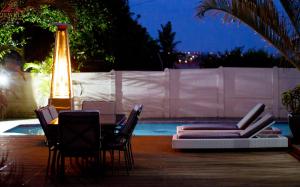 una mesa y sillas junto a una piscina por la noche en JFT Jewels Guest House en East London