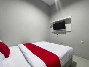 um quarto com uma cama com um cobertor vermelho e uma televisão em RedDoorz Near Rumah Sakit Soewandhie em Surabaia