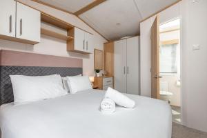 um quarto com uma grande cama branca com almofadas brancas em Lodge 10 The Silverdale Close to St Andrews em St Andrews