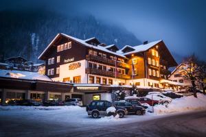 ein Hotel mit Autos auf einem Parkplatz im Schnee in der Unterkunft Posthotel Rössle in Gaschurn