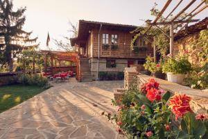 a house with a patio and flowers in front of it at Yovina House Zheravna in Zheravna
