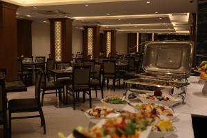 un comedor con mesas, sillas y comida en Coral Hotel Karbala en Karbalāʼ