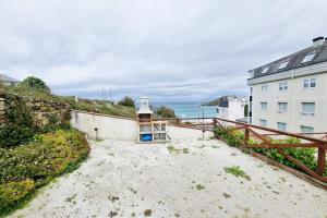 a lighthouse on a beach next to a building at VibesMalpica - Canido 12 in Malpica