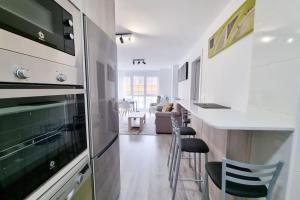 a kitchen with a stove and a counter with chairs at VibesMalpica - Canido 12 in Malpica