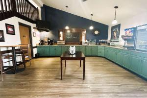a large kitchen with green cabinets and a table at AmericInn by Wyndham Menominee in Menominee