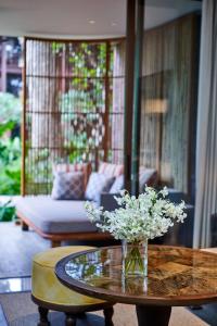 eine Vase mit Blumen auf einem Tisch im Wohnzimmer in der Unterkunft Andaz Bali - a Concept by Hyatt in Sanur