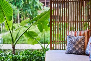 a couch with a pillow on it in a garden at Andaz Bali - a Concept by Hyatt in Sanur