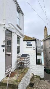 a small white house with a table in front of it at SMUGGLERS HIDE COTTAGE and separate but connecting SMUGGLERS CABIN - - In a beautifully renovated fishermans cottage - - HARBOUR VIEWS - - BEACH only 10 metres - - RENOVATION AWARDS WINNER - - Book Both For An Even Larger Property in St Ives