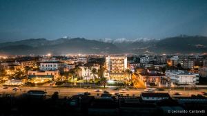 uma vista para uma cidade à noite com montanhas em Hotel Excelsior em Marina di Massa