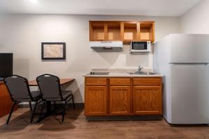 a kitchen with a white refrigerator and a table and chairs at WoodSpring Suites Greenville Simpsonville in Simpsonville