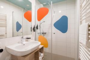 a bathroom with a sink and orange hearts on the wall at Ramada Encore by Wyndham Munich Messe in Munich