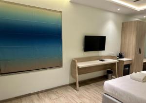 ein Hotelzimmer mit einem Schreibtisch und einem TV an der Wand in der Unterkunft World Inn Hotel in Visakhapatnam