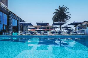 einen Pool mit Sonnenschirmen, Stühlen und einer Palme in der Unterkunft Hotel Excelsior in Marina di Massa