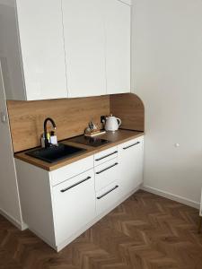a kitchen with white cabinets and a sink at Apartament Planeta 106 - tylko 100 m od plaży in Mielno