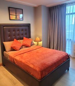 a bedroom with a large bed with an orange blanket at Gramercy staycaytion in Manila