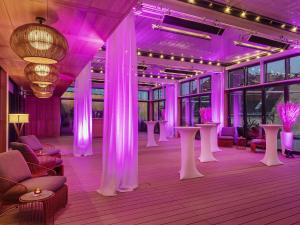 Zimmer mit violetter Beleuchtung sowie Tischen und Stühlen in der Unterkunft Pullman Budapest in Budapest