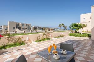 einen Tisch mit Tassen und Untertassen auf einer Terrasse in der Unterkunft Hotel Caretta Beach in Gerani Chania