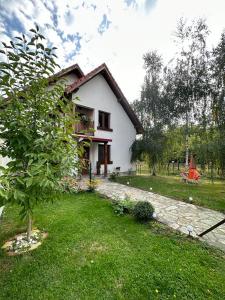 a small white house with a tree in the yard at CONACUL DE SUB MUNTE in Novaci-Străini