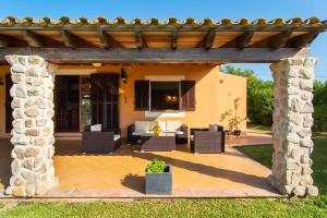 an outdoor patio with chairs and a pergola at Finca Pollentia in Alcudia