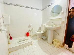 a white bathroom with a sink and a toilet at Hotel Miandam Palace in Mingāora