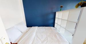 - une petite chambre avec un lit blanc et un mur bleu dans l'établissement Le Central tout équipé !, à Toulouse