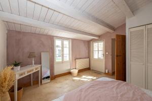 um quarto com uma cama, uma secretária e janelas em Charmante maison dans venelle fleurie em Sainte-Marie-de-Ré