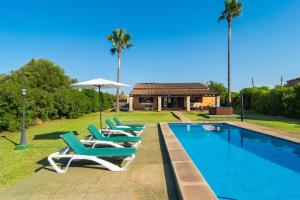 a swimming pool with lounge chairs and an umbrella at Finca Pollentia in Alcudia