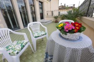 2 weiße Stühle und ein Tisch mit einer Vase Blumen in der Unterkunft La terrazza di Villa Edera in Treviso